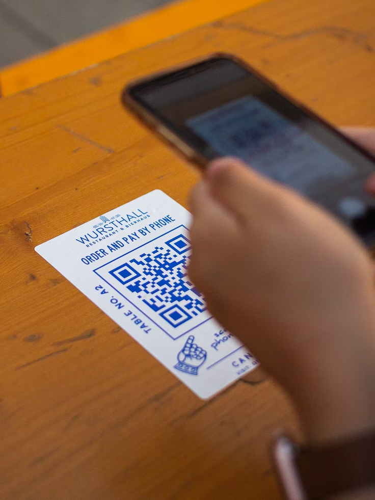 Image of someone scanning a QR code in a restaurant with their phone to order their meal