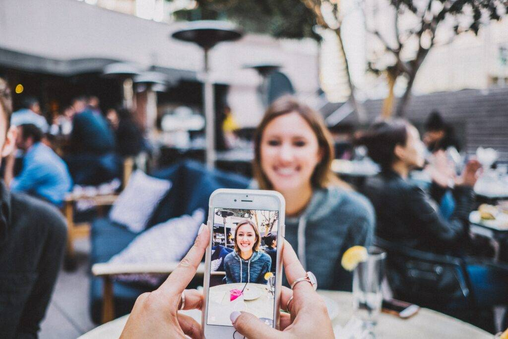 Someone taking a photo of a female diner in a restaurant with a mobile phone