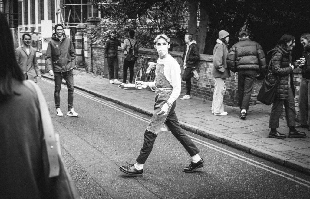 waiter in a mask carrying food across a road